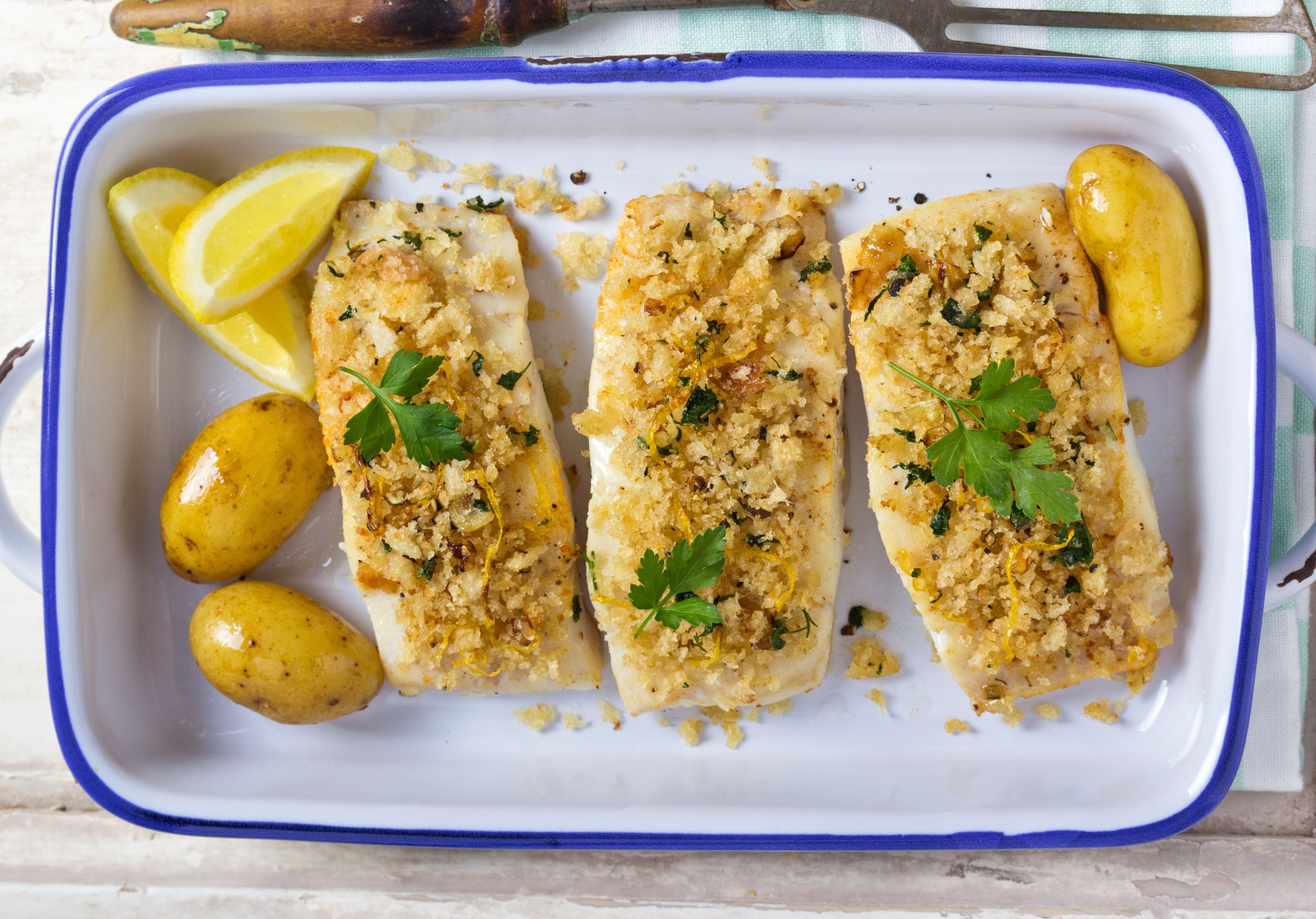 Cheddar and chives crusted cod ready to bake displayed with potatoes and lemon wedges. King George's Steak and Seafood. 