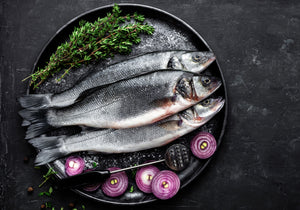 Entire European sea bass fish served on a skillet with red onions and rosemary. King George's Steak and Seafood.