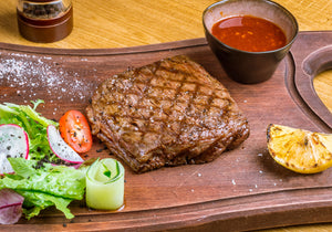 Grilled flat iron steak served with salad, lemon wedge, and spicy sauce. King George's Steak and Seafood.