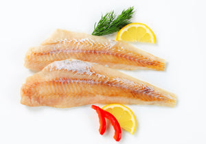 Raw Haddock Fillets displayed with rosemary, lemon wedges, and red chili slices. King George's Steak and Seafood. 