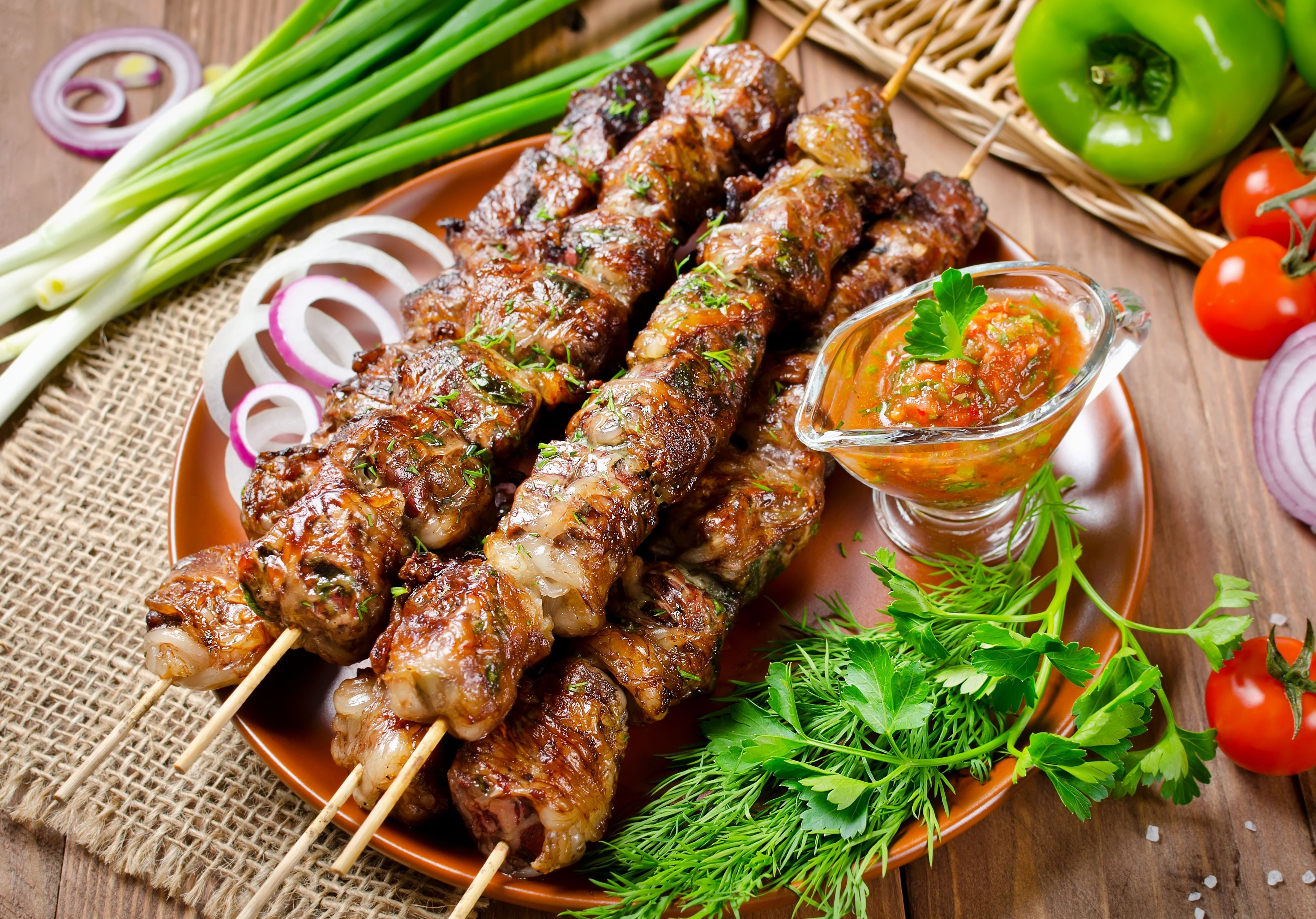 Cooked beef kebabs displayed with cilantro, rosemary, tomato sauce, green peppers, and green onions. King George's Steak and Seafood.