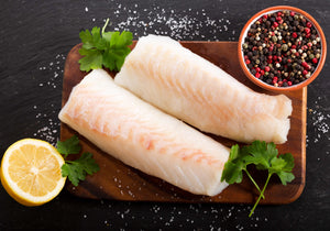 Raw cod fillets displayed with peppercorns, sea salt, cilantro and lemon. King George's Steak and Seafood.