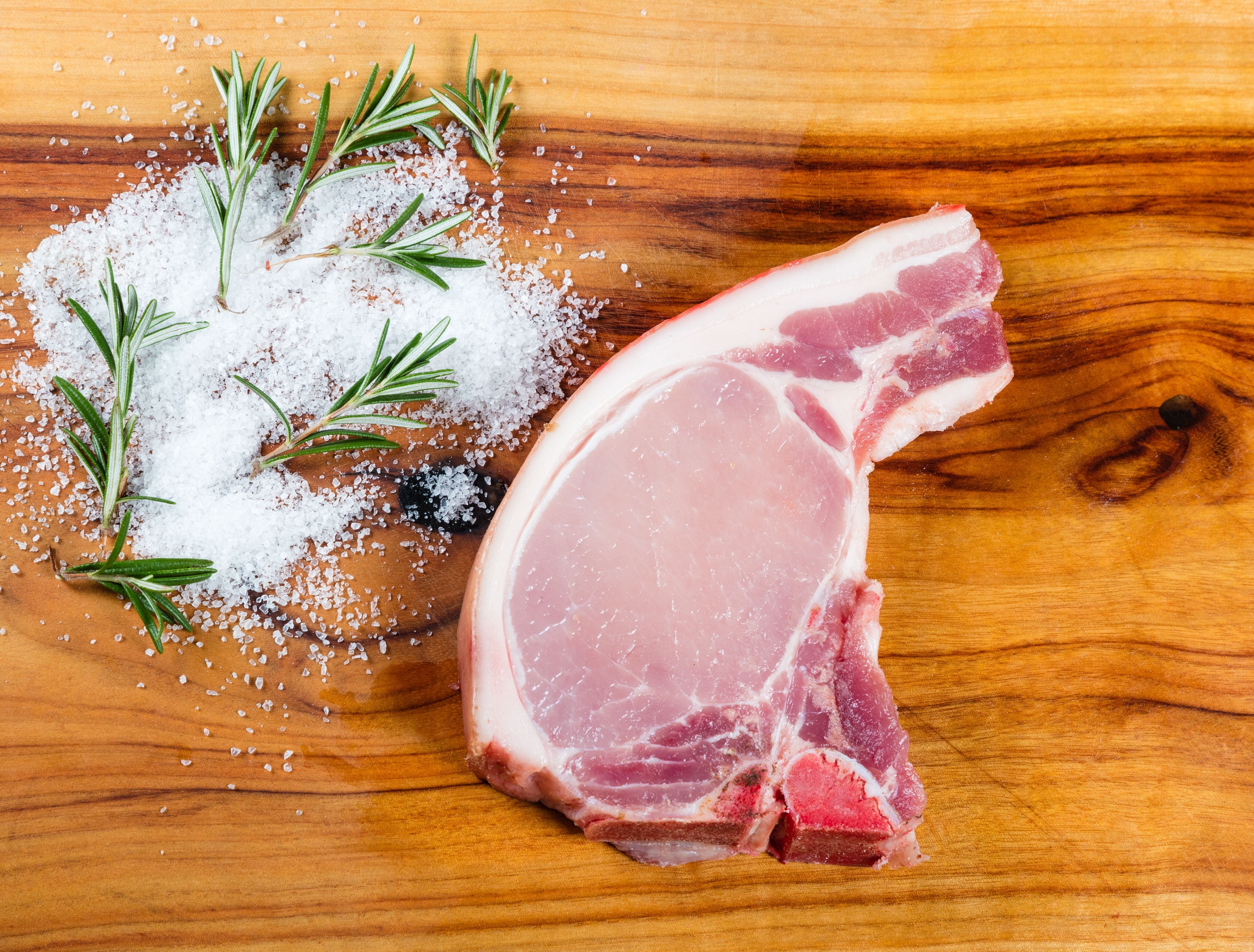 Berkshire pork chops (with short bone) raw with sea salt and rosemary. King George's.