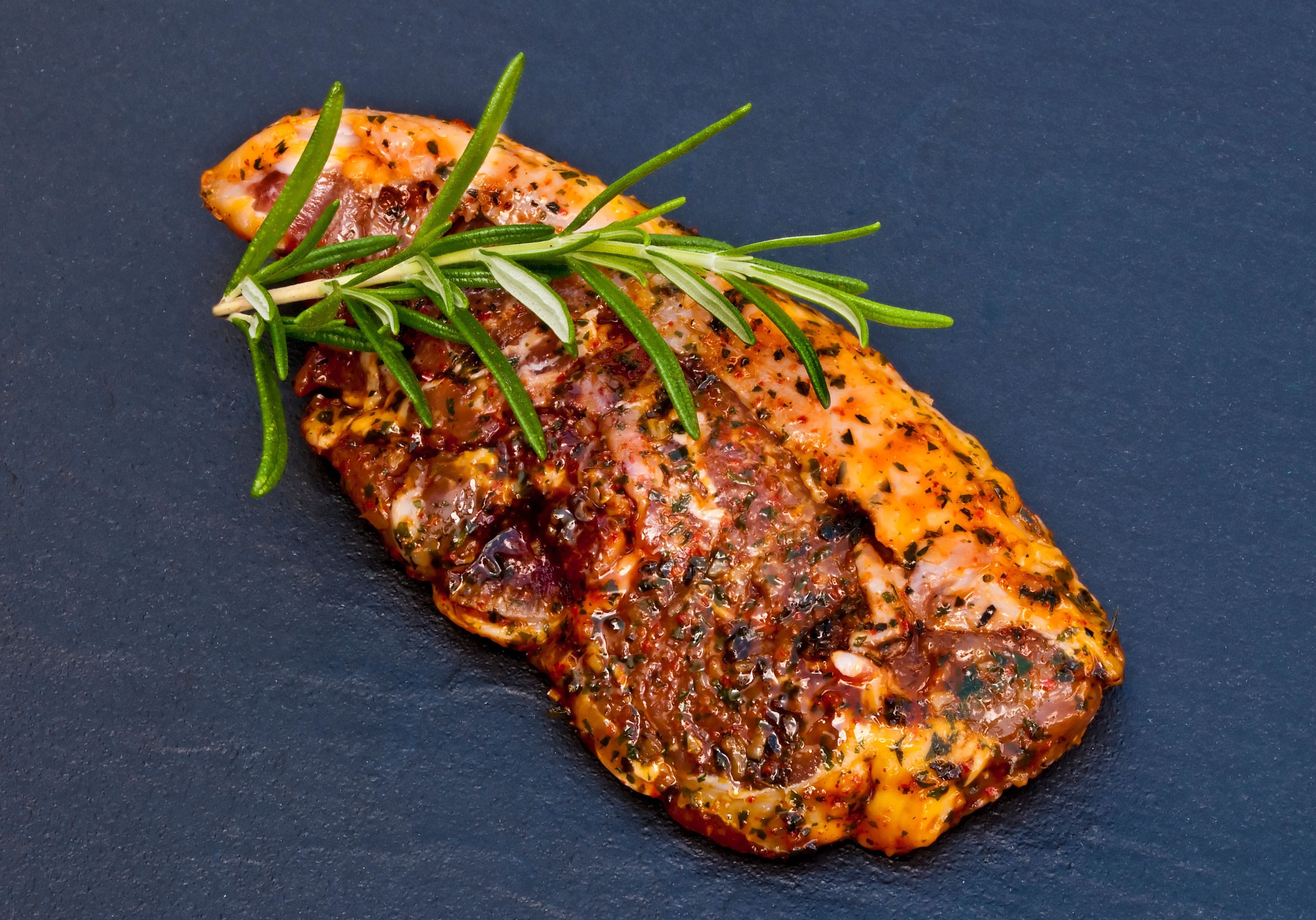 Raw Lamb Steak marinaded with spices and garnished with fresh rosemary. King George's Steaks and Seafood.