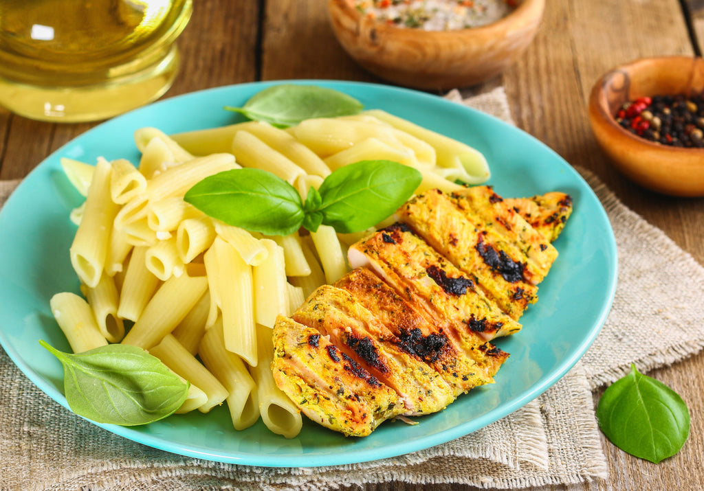 Lemon chicken grilled and served with fresh pasta, garnished with fresh basil leaves. King George's Steaks and Seafood.