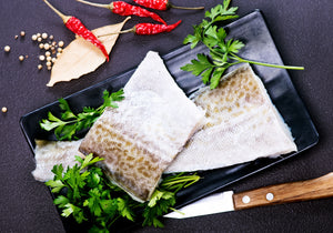 Raw pickerel fish fillets with skin displayed on a plate garnished with peppercorn, parsley, dried red chili peppers. King George's Steaks and Seafood.