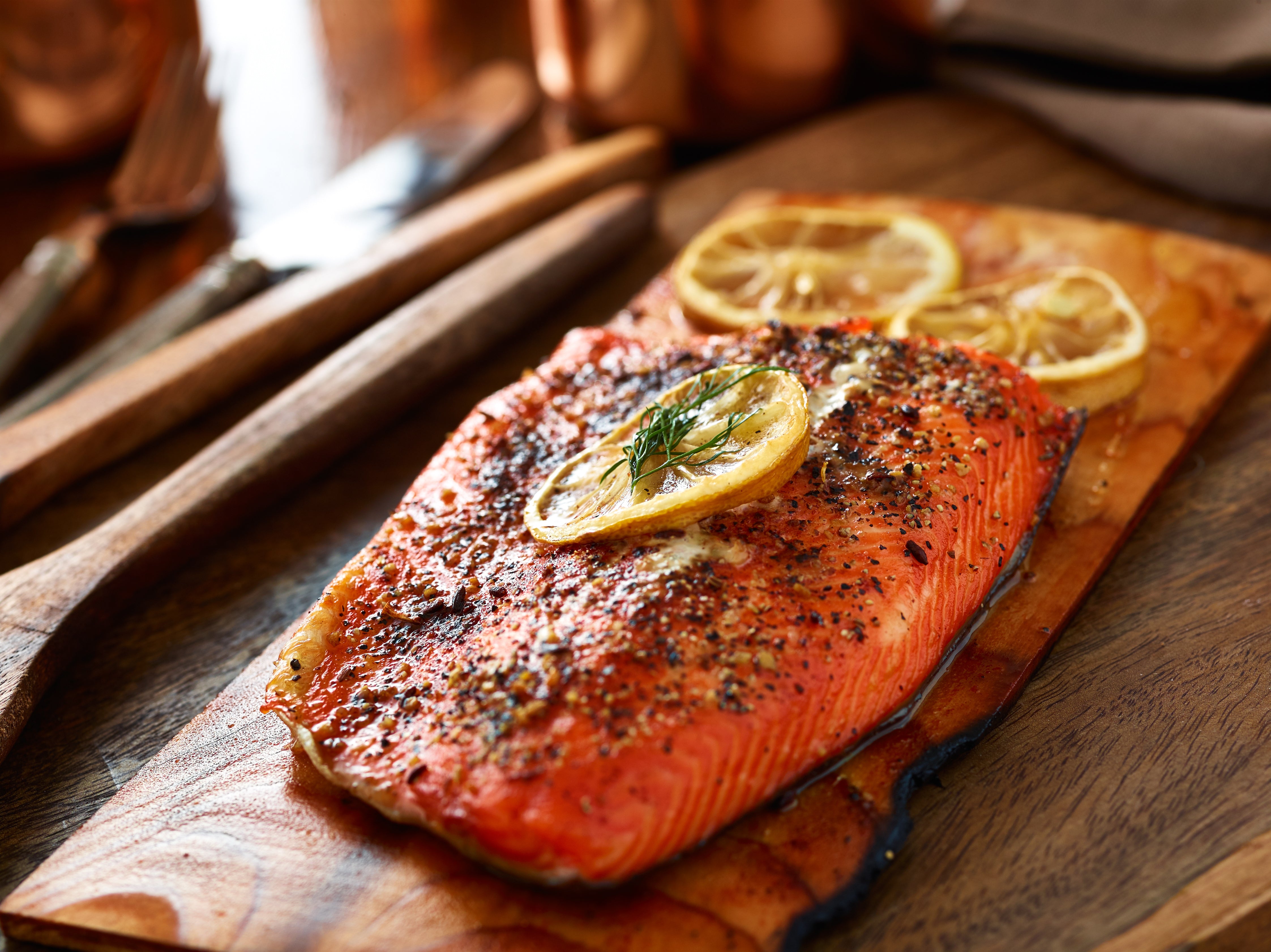 Cedar plank salmon cooked with spices and lemon slices. Served on top of the cedar plank and with fresh dill garnish. King George's Steak and Seafood. 