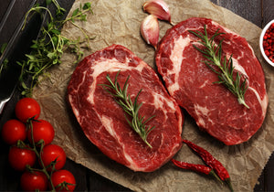 Two Rib Eye Prime fillets displayed with sea salt, garlic, dry red chili, peppercorn, and rosemary. King George's Steaks and Seafood.