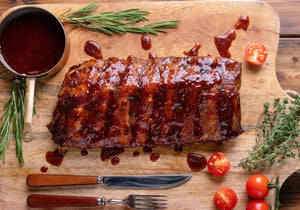 Grilled Steakhouse Ribs drizzled with barbecue sauce, garnished with rosemary, cherry tomatoes, and oregano leaves. King George's Steaks and Seafood.