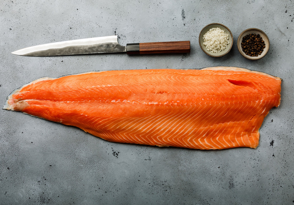 Raw Trout fillet displayed with peppercorn, sea salt, and a knife. King George's Steak and Seafood.