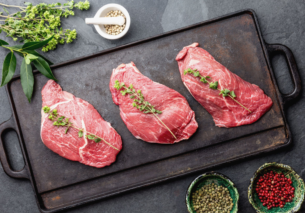 Three raw Veal Scaloppini fillets ready to be baked, displayed with peppercorn, and other spices. King George's Steak and Seafood.  