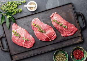 Three raw Veal Scaloppini fillets ready to be baked, displayed with peppercorn, and other spices. King George's Steak and Seafood.  